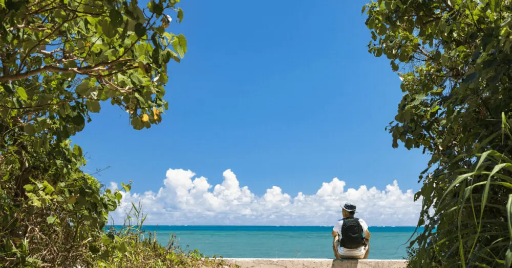 沖縄の空と海の前にたたずむ男性旅行者